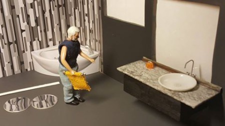 Badrumsskåpet med handfat är i balsaträ, en liten tallrik och en tapetbit som yta. Kranen är ett gem.